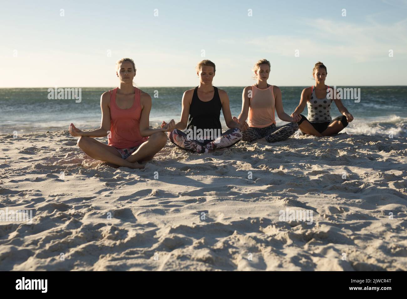 Femmes faisant du yoga sur la plage Banque D'Images