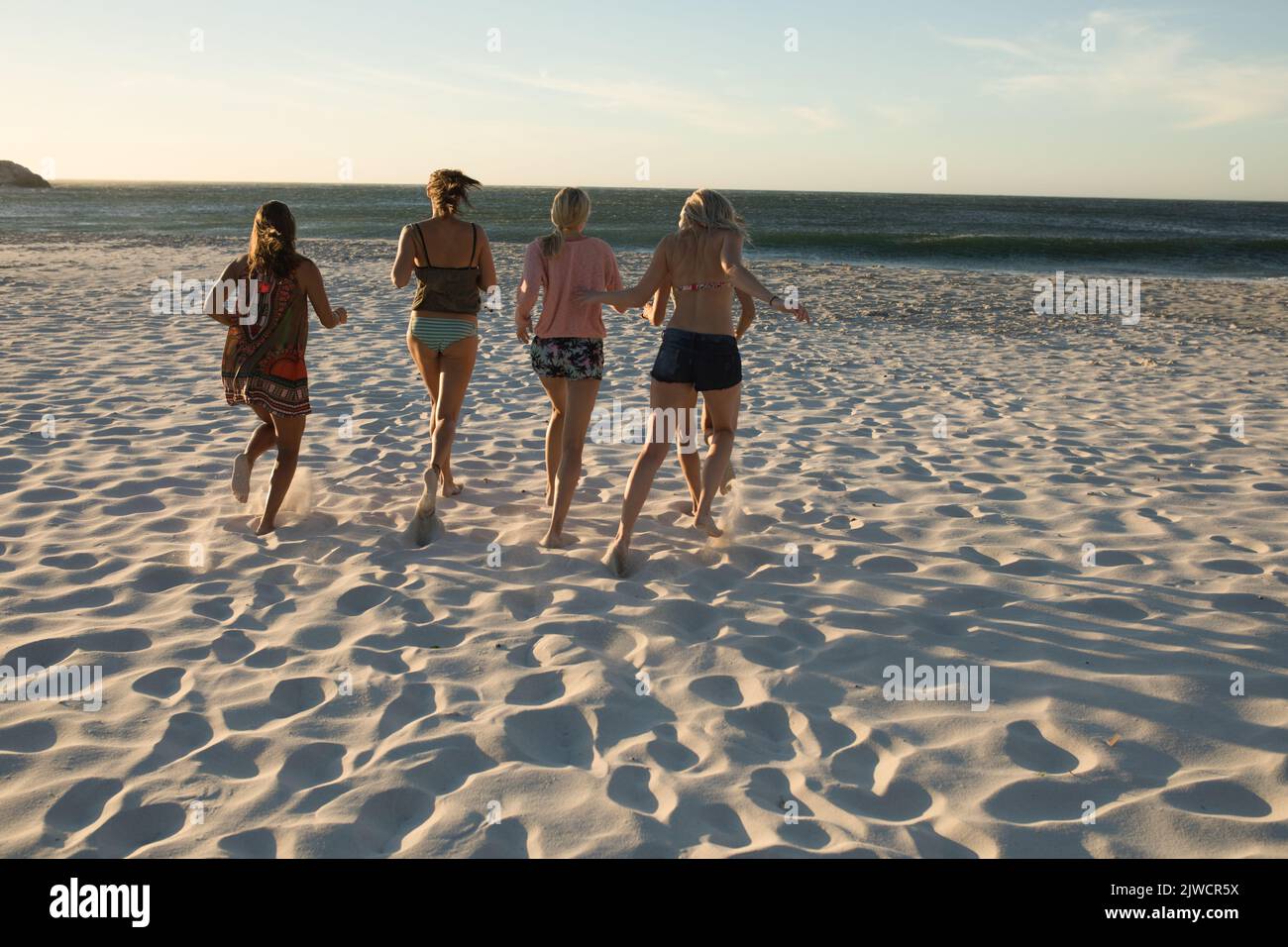 Les femmes qui couperaient sur la plage au coucher du soleil Banque D'Images