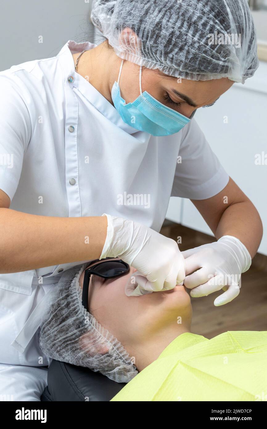 Dentiste installant un rétracteur de joue de patient dans un cabinet de dentiste Banque D'Images Dentiste installant un rétracteur de joue de patient dans un cabinet de dentiste Banque D'Images