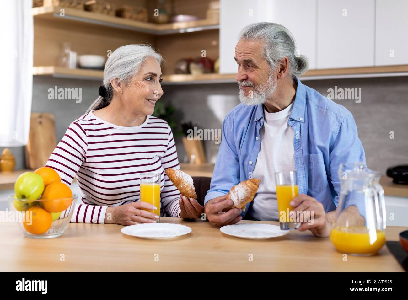Portrait d'un couple de personnes âgées gaies prenant le petit déjeuner ensemble dans la cuisine intérieure Banque D'Images