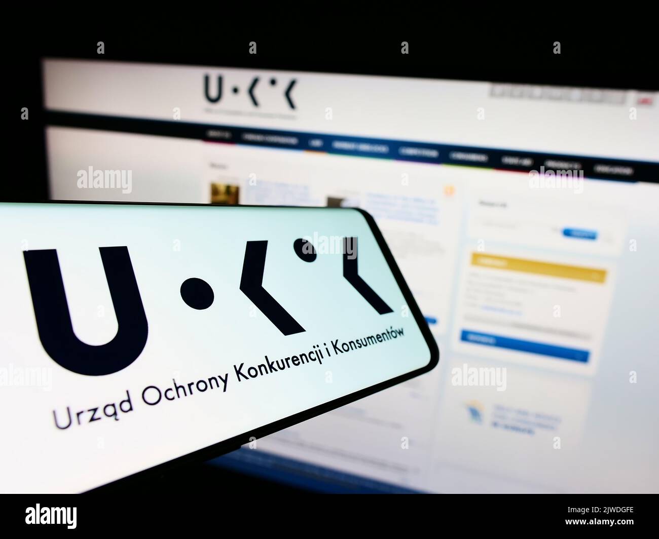 Téléphone mobile avec logo de l'autorité polonaise de la concurrence UOKiK à l'écran en face du site Web. Effectuez la mise au point au centre-droit de l'écran du téléphone. Banque D'Images