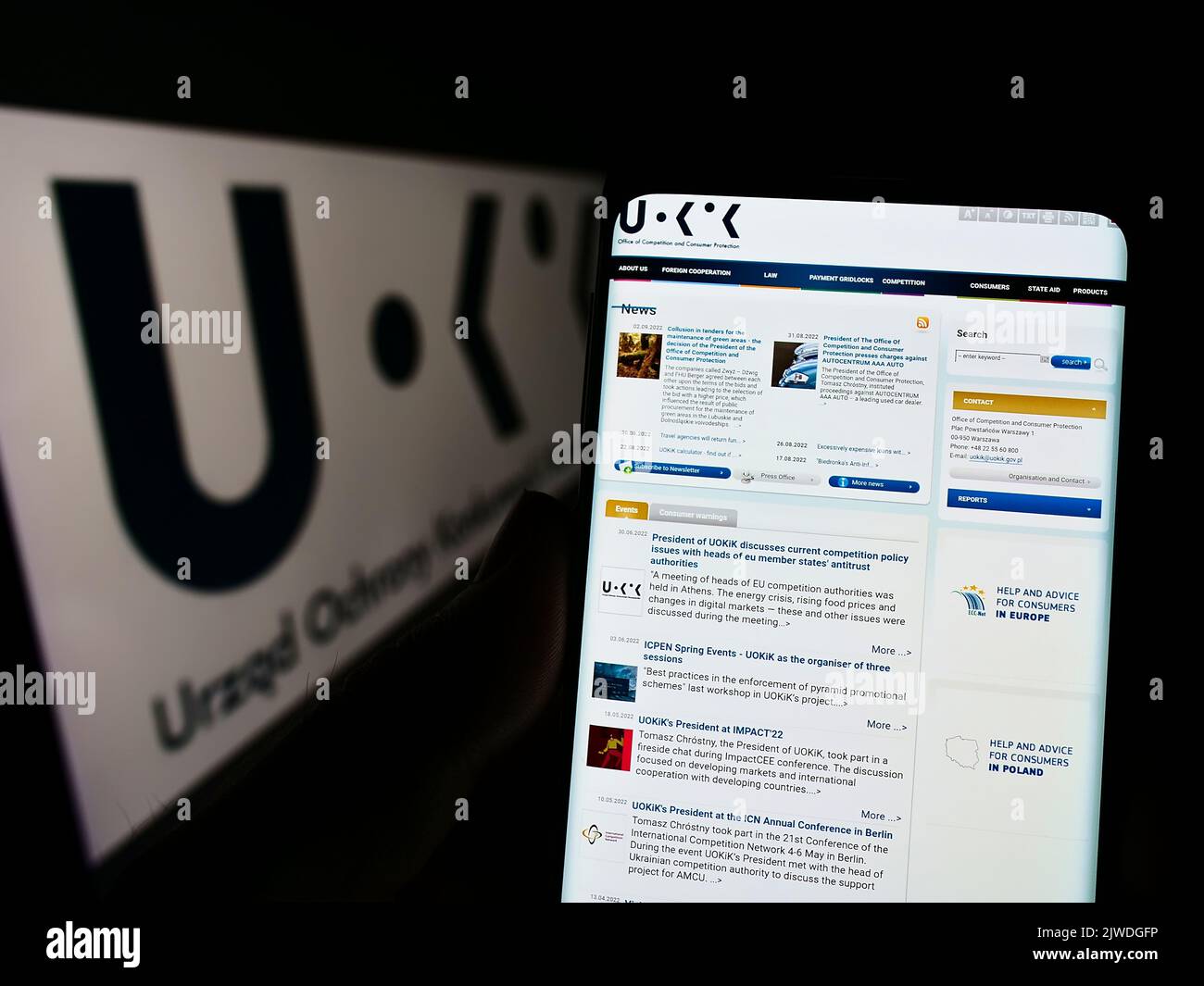 Personne tenant un téléphone portable avec le site web de l'autorité polonaise de la concurrence UOKiK à l'écran devant le logo. Concentrez-vous sur le centre de l'écran du téléphone. Banque D'Images