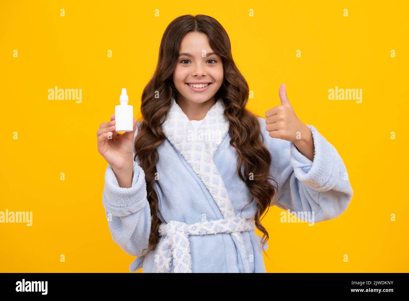 Une adolescente tient le médicament spray nasal du nez courant, une pandémie de virus. Jeune fille malade avec vaporisateur nasal sur fond jaune. Banque D'Images
