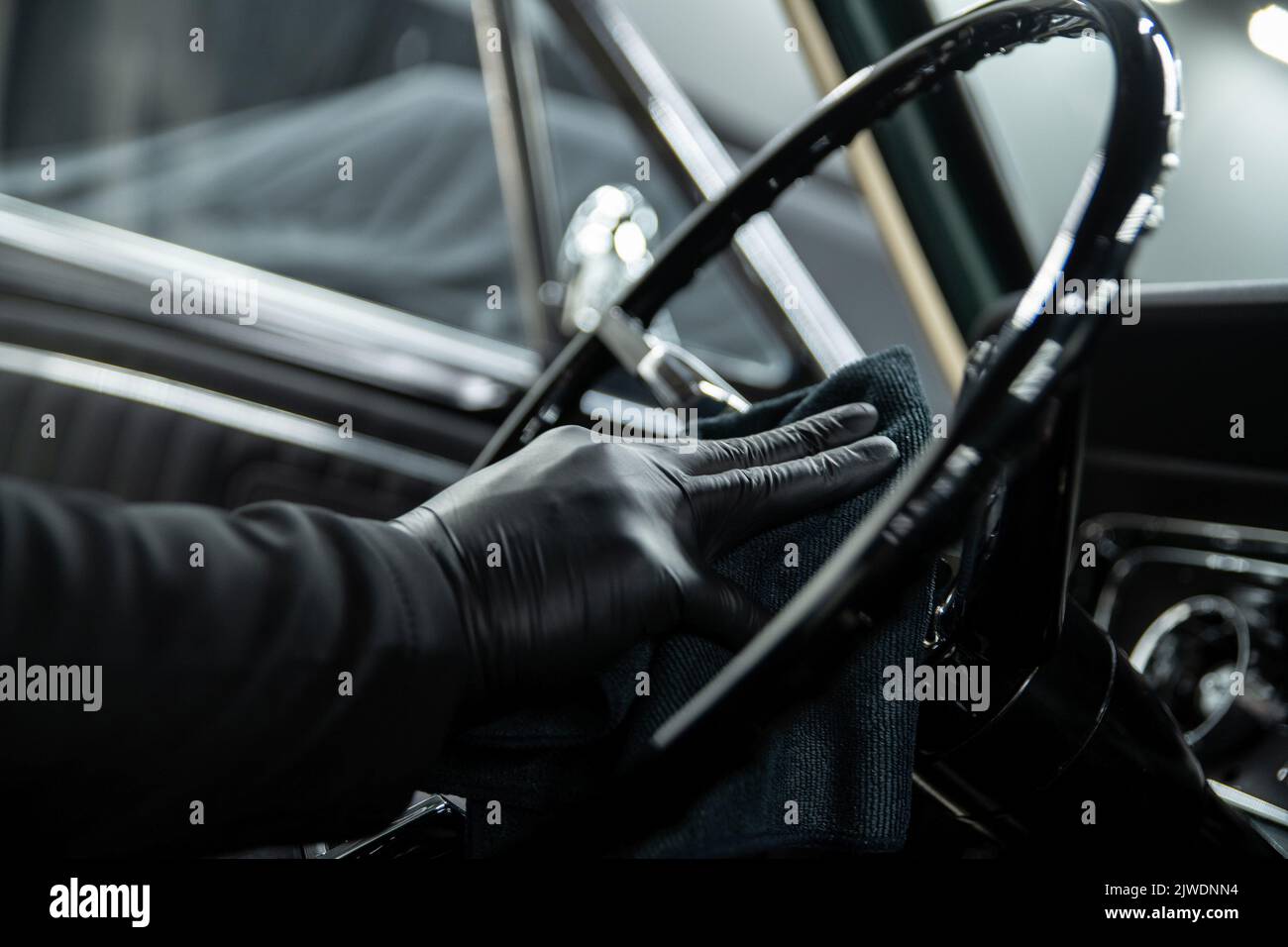 Un employé d'un lave-auto ou d'un studio de nettoyage de voiture nettoie un volant Banque D'Images