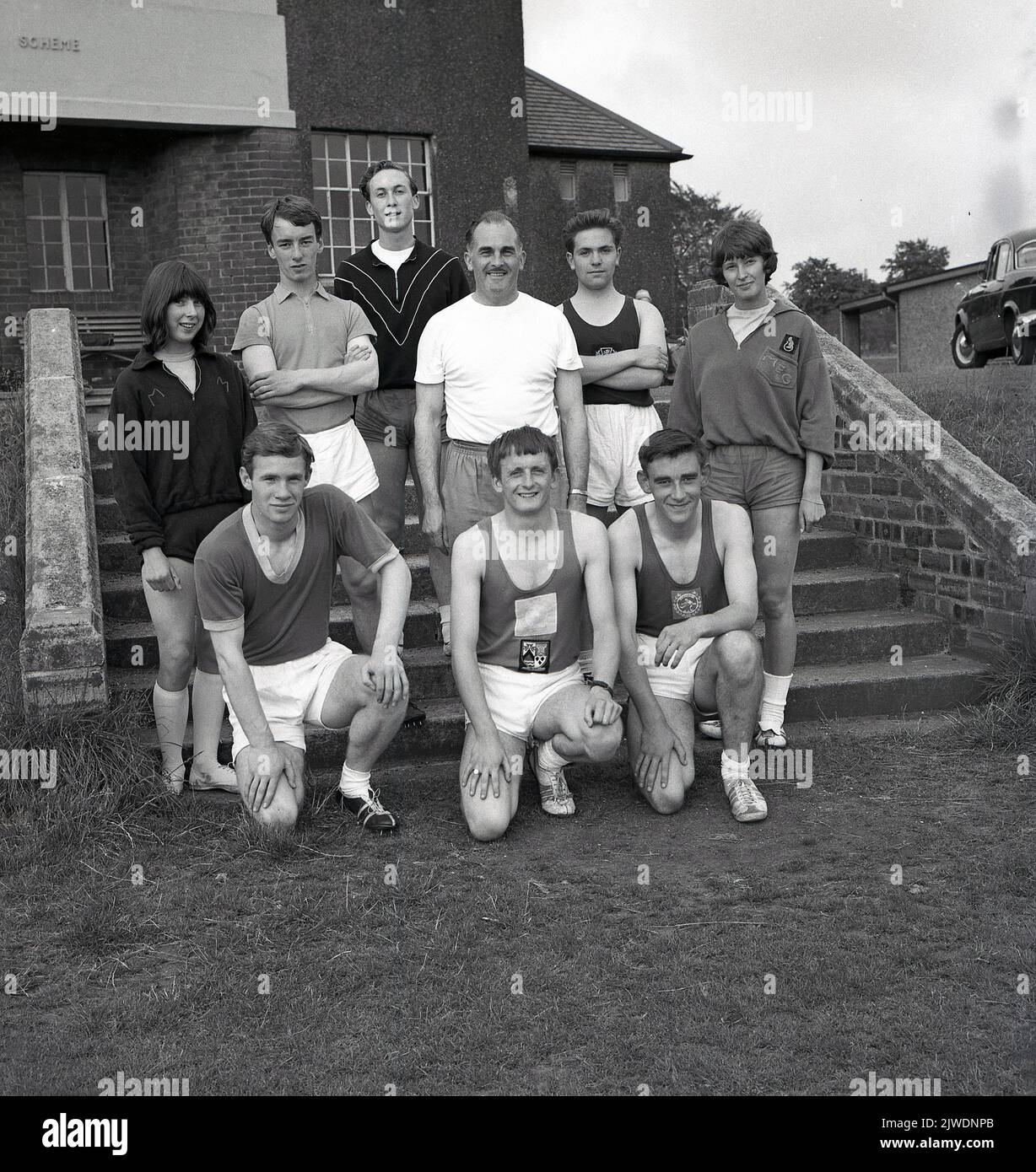 1960s, historique, les jeunes adultes membres d'un club d'athlétisme amateur posent à l'extérieur pour une photo de groupe, avec leur entraîneur masculin, Écosse, Royaume-Uni. Banque D'Images