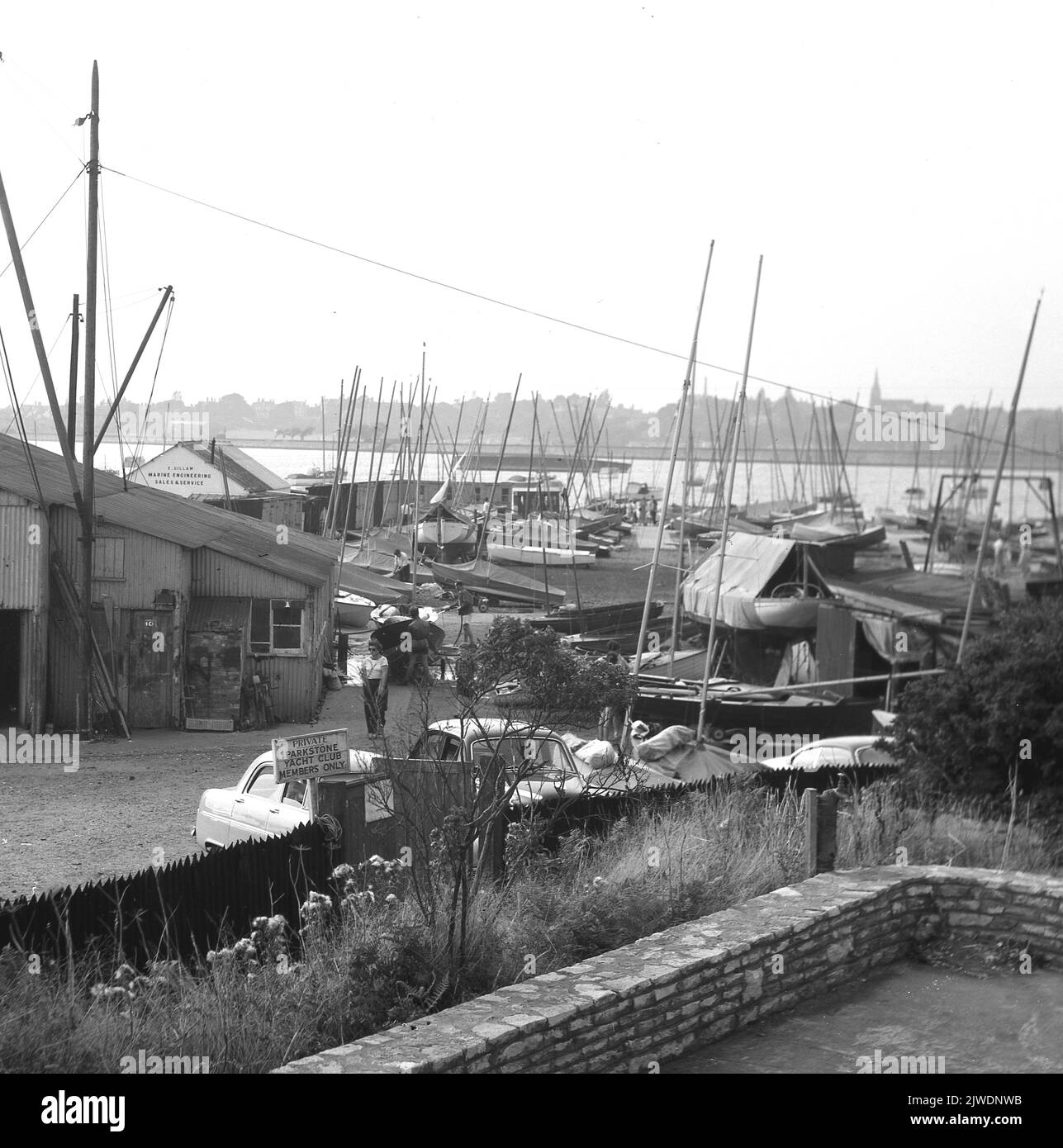 1960, historique, vue sur Parkstone Yacht Club, Poole, Dorset, Angleterre, Royaume-Uni, Présenter des bateaux et divers hangars de réparation marine, y compris celui de E. Gillam, Marine Engineering, Sales & Service. Situé sur la rive nord du port de Poole, le deuxième plus grand port naturel au monde, le Yacht Club a été créé en 1895. Banque D'Images