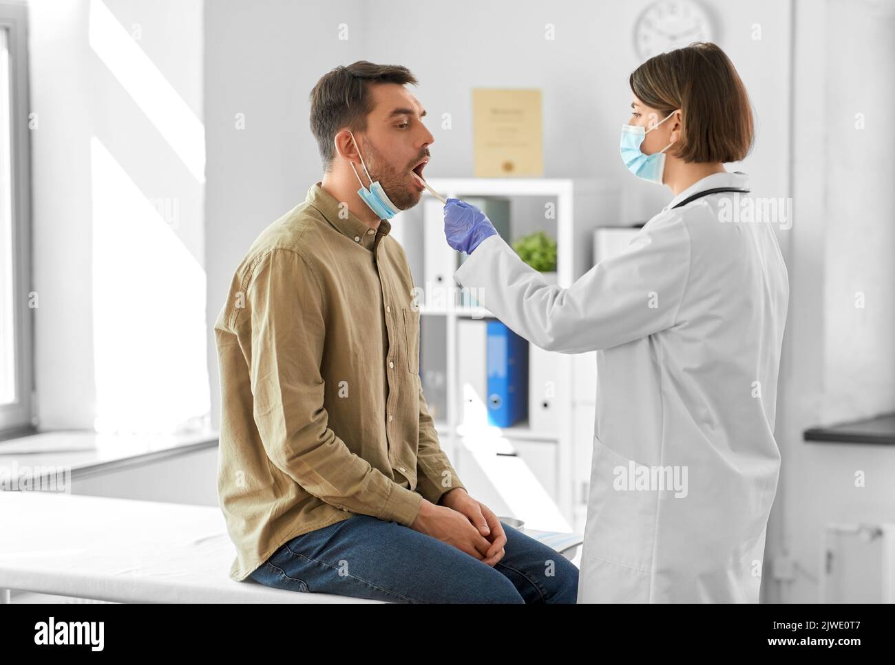 médecin vérifiant la gorge du patient mâle à l'hôpital Banque D'Images