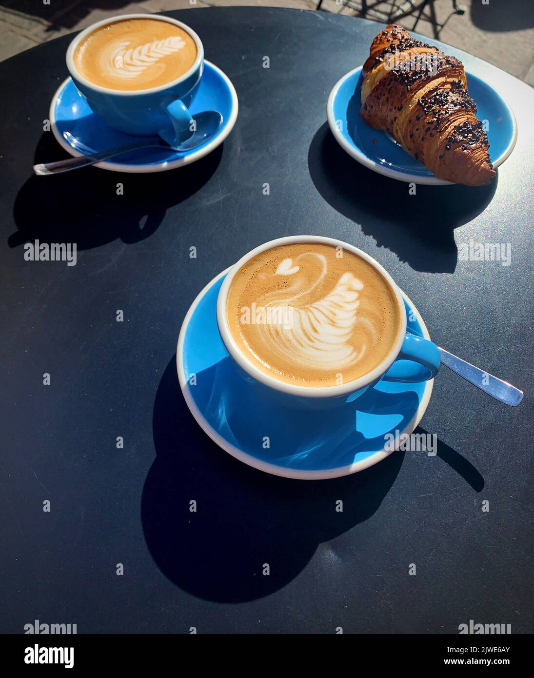 Deux tasses de cappuccino et un croissant sur une table Banque D'Images