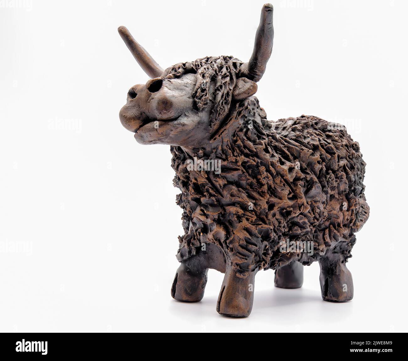 Gros plan détaillé d'une figurine scottish Red highland en argile fabriquée à la main (Bò Ghàidhealach; Hielan coo) avec cornes complètes, fond blanc Banque D'Images