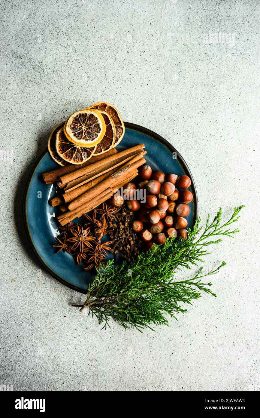 Vue en hauteur sur les bâtonnets de cannelle, l'anis étoilé, les noisettes, les clous de girofle, les tranches d'orange séchées et les branches de thuja Banque D'Images