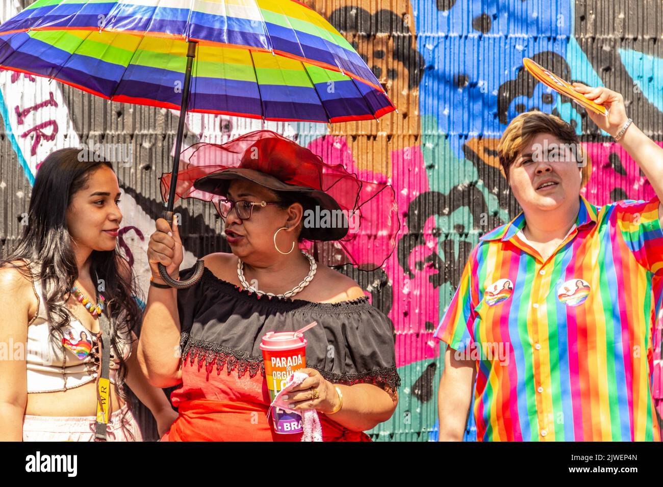 Goias, Brésil – 05 septembre 2022 : deux personnes parlent sous le parapluie et une autre personne à côté d'eux dans des vêtements colorés, regardant vers le haut. Banque D'Images