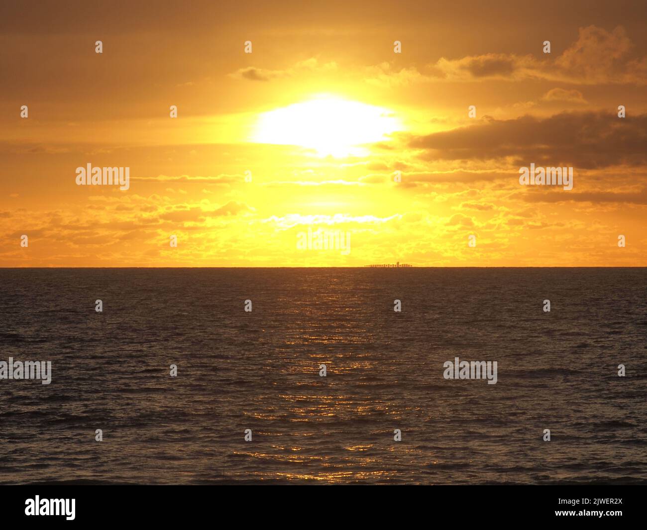 Lever du soleil le long du littoral du New Jersey avec un bateau à conteneurs silhoueté à l'horizon lointain. En direction du port de Newark, la vapeur se dirige lentement vers le nord. Banque D'Images