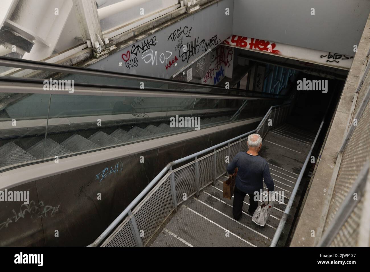 Bucarest, Roumanie - 3 septembre 2022: Un homme de haut niveau descend un escalier sombre, sale et vandalisé à Bucarest. Banque D'Images