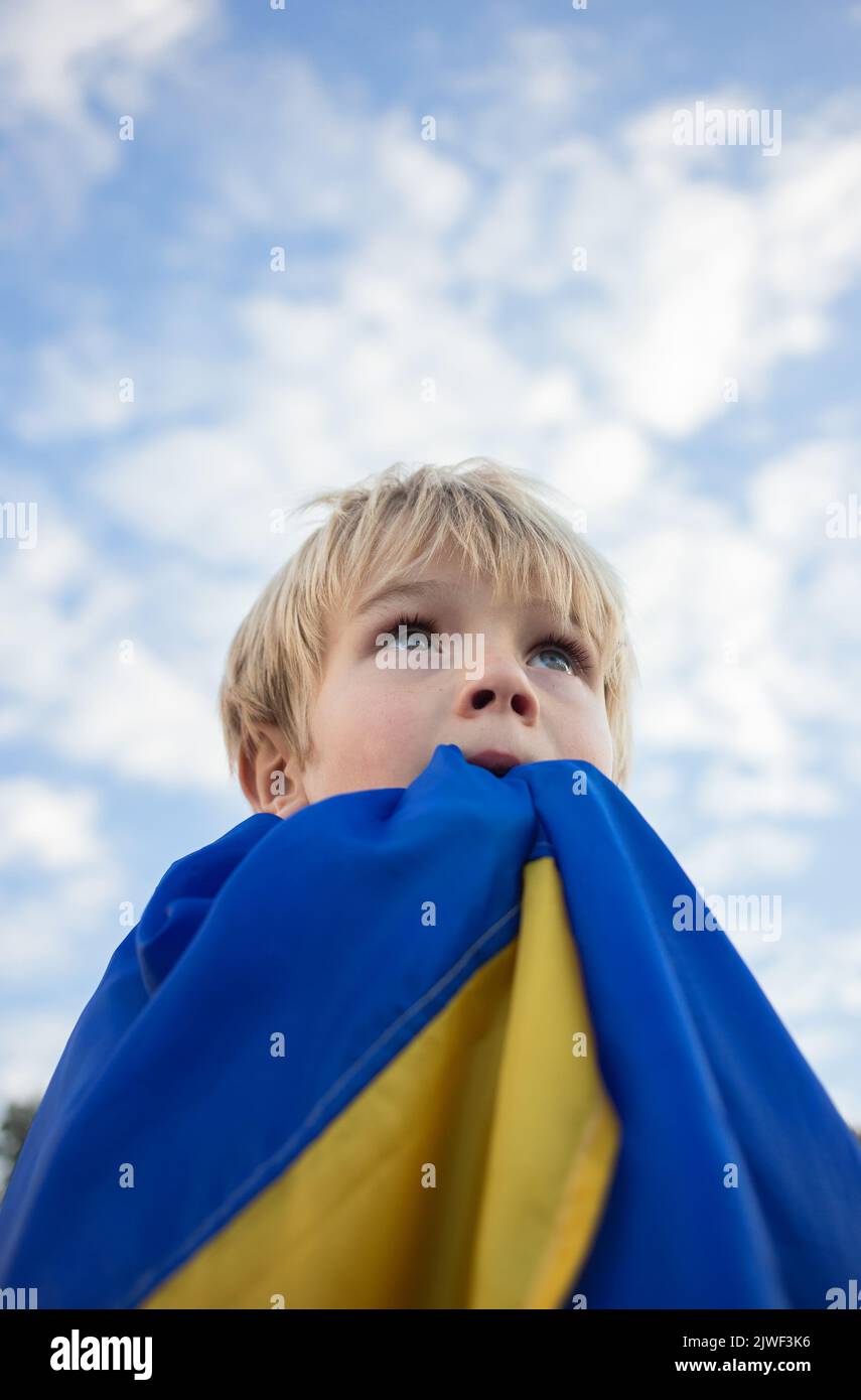 Les yeux de l'enfant regardent le ciel, le visage est couvert de drapeau ukrainien. Symbole national de liberté et d'indépendance. Invasion russe de l'Ukraine, Arrêter la guerre. Hai Banque D'Images