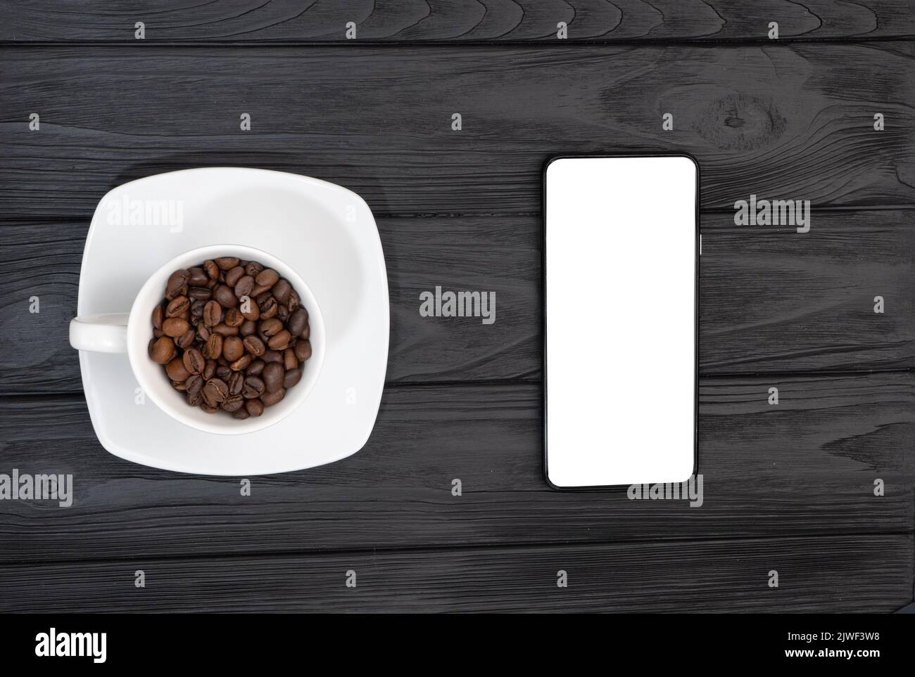 Vue de dessus d'un smartphone vide et d'une tasse de café avec des grains. Espace vide blanc pour le logo de la publicité Banque D'Images