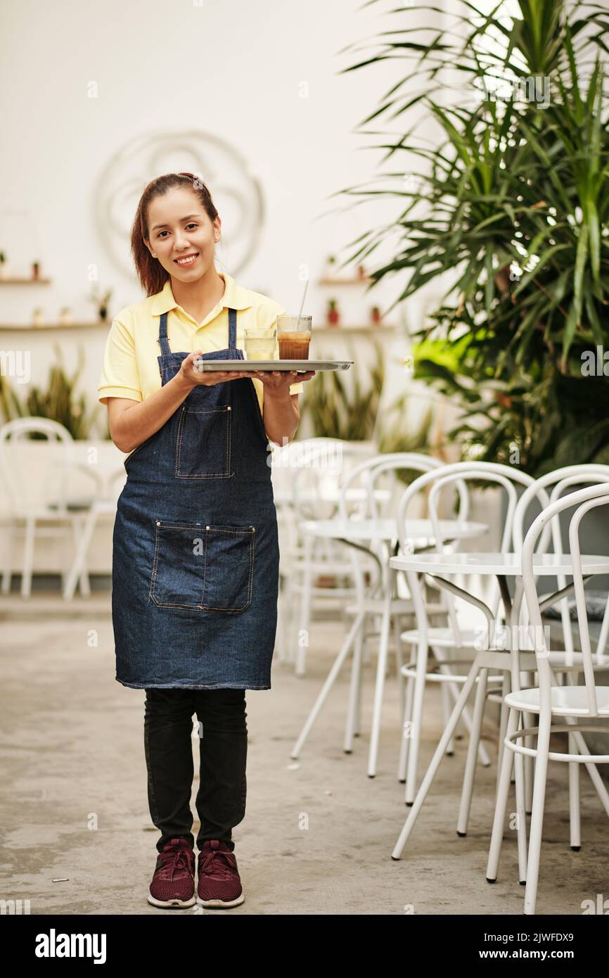 Plateau de serveuse souriant avec verres de café glacé et d'eau Banque D'Images