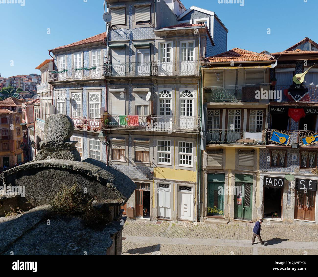 Les bâtiments traditionnels de Porto avec des balcons tandis qu'un homme âgé marche le long de la rue. Un spectacle Fado avec guitares à l'extérieur est sur la droite. Banque D'Images