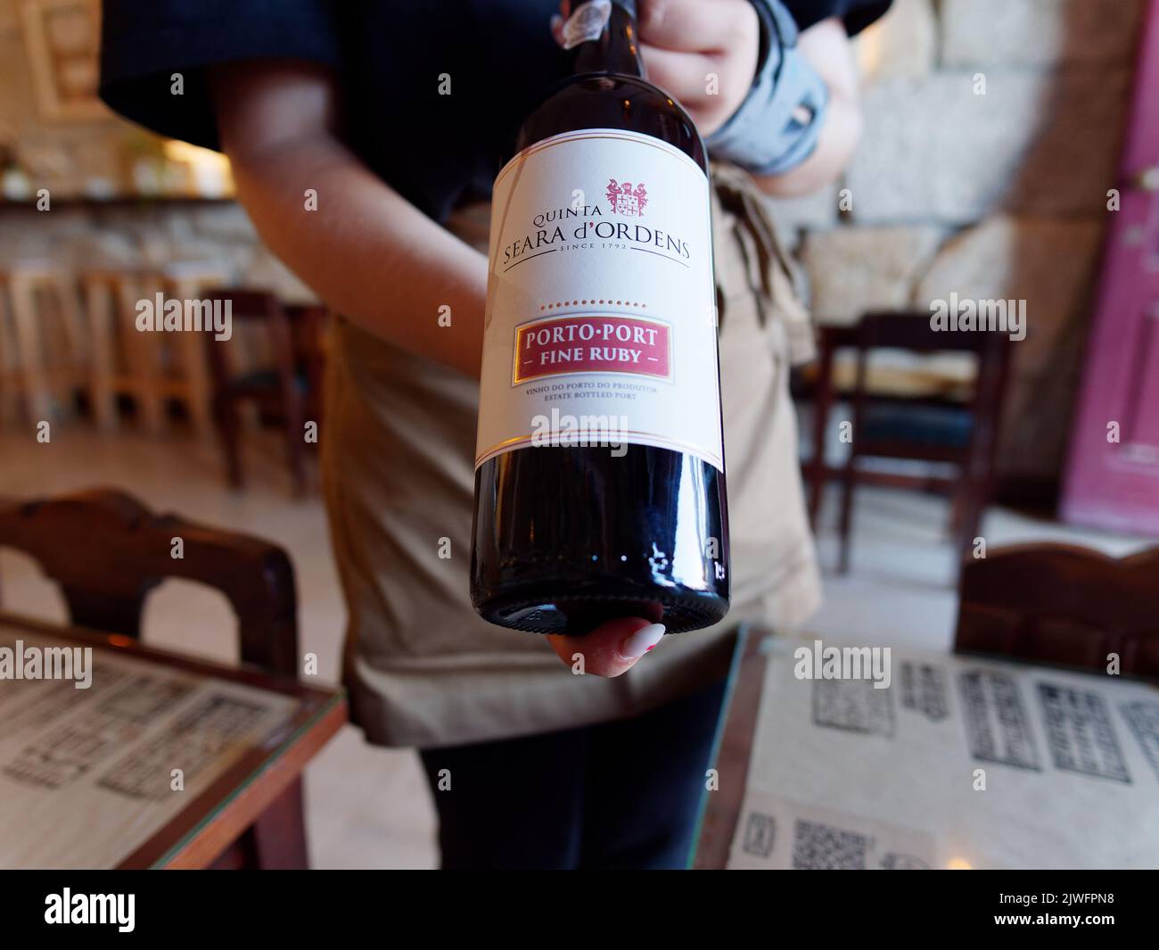 La serveuse présente une bouteille de vin du port de rubis dans un restaurant traditionnel de dégustation de vins dans le quartier de Ribeira à Porto, au Portugal Banque D'Images
