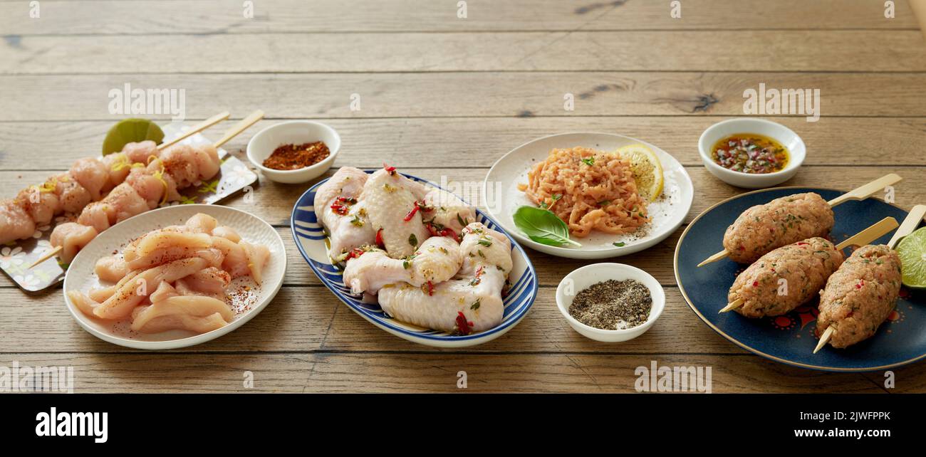 De ci-dessus différents types de viande de poulet non cuite servi sur une table en bois avec diverses épices dans la cuisine légère pendant le processus de cuisson Banque D'Images