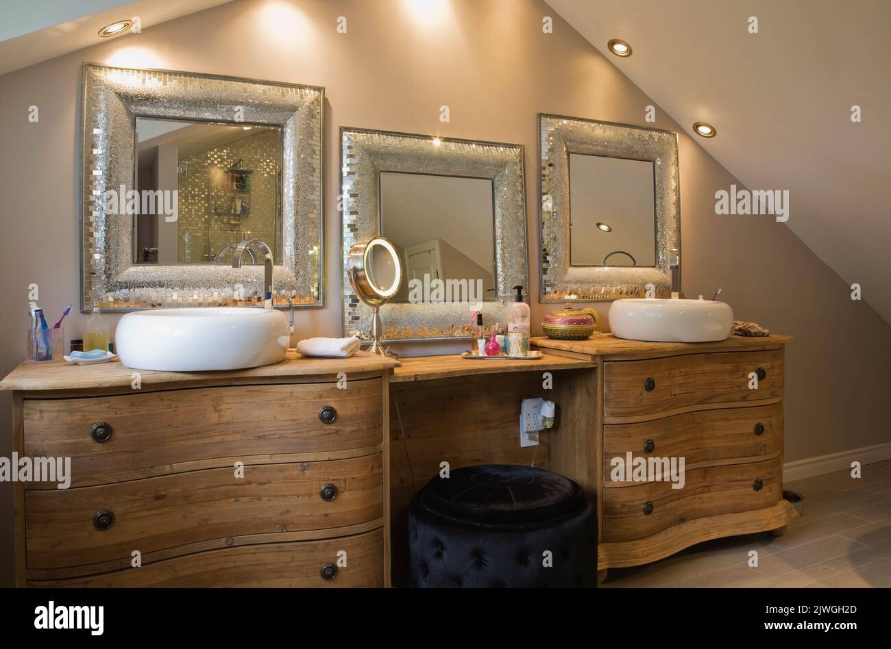 Salle de bains principale avec armoires en bois et miroirs encadrés d'argent à l'intérieur d'une luxueuse maison. Banque D'Images