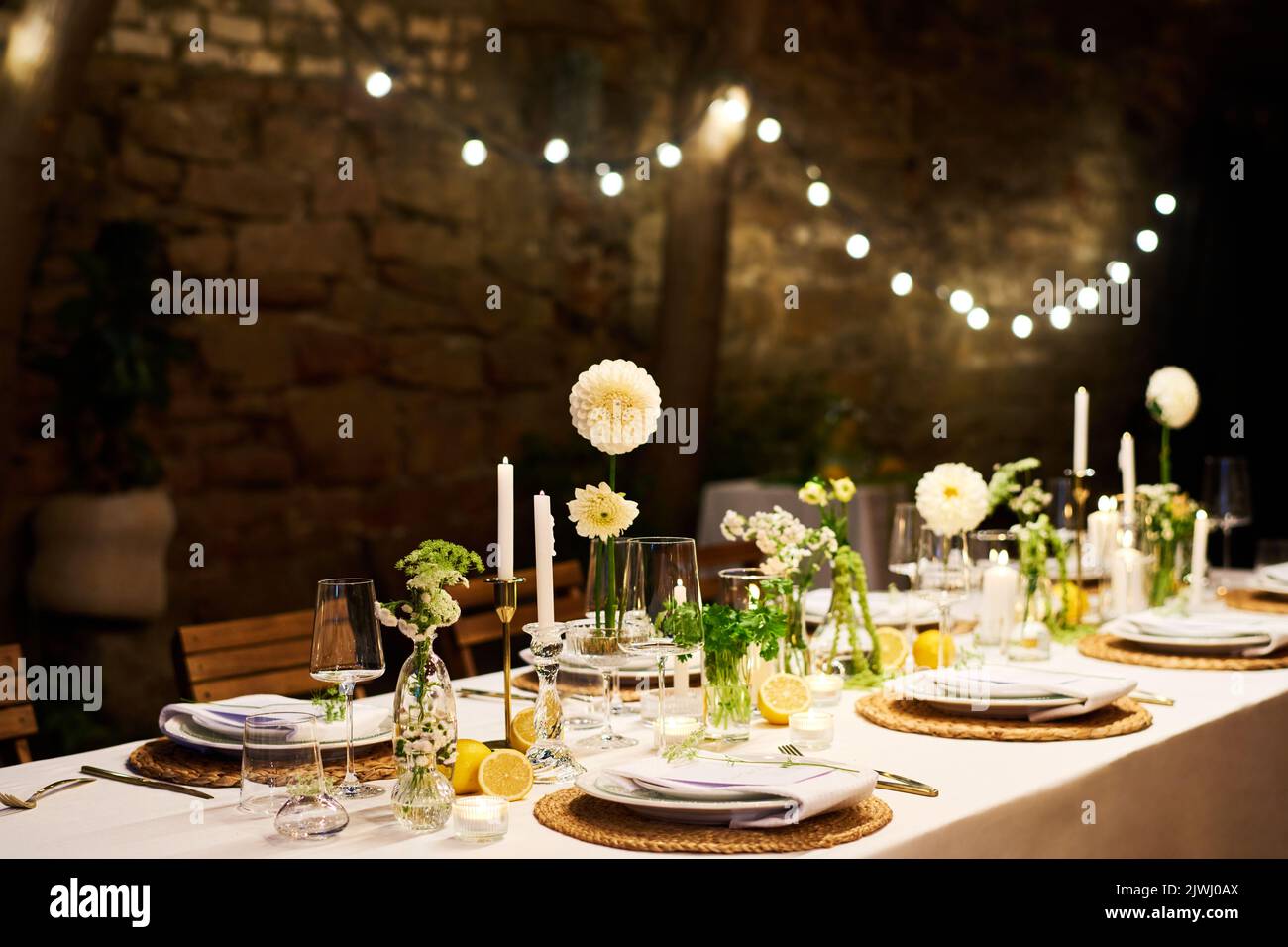 Table de dîner avec assiettes, serviettes, verres à vin, fleurs et bougies préparés pour le mariage dans un restaurant ou un café luxueux Banque D'Images