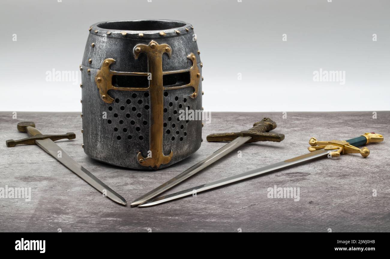 Casque chevalier médiéval et épées isolés sur une table en pierre. Banque D'Images