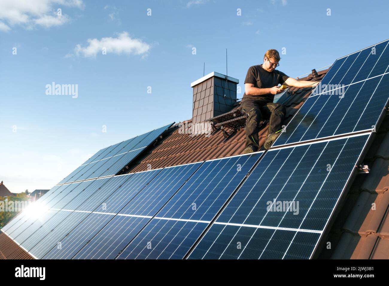 Technicien vérifiant le système photovoltaïque sur le toit d'une maison Banque D'Images