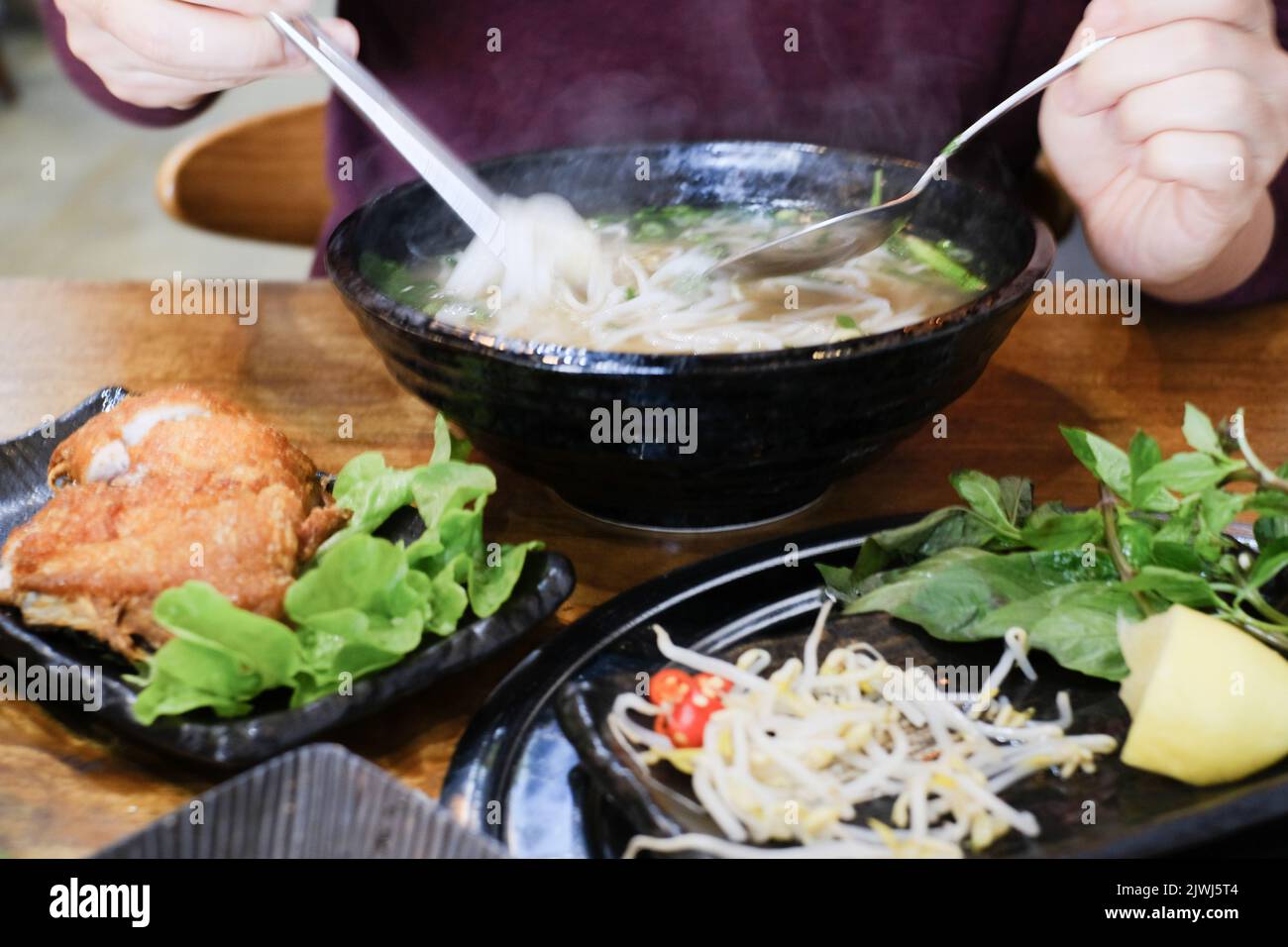 Homme mangeant un bol de Phở Bò (bof pho) et de Gà Da Dòn (poulet croustillant) à Me Pho, un restaurant vietnamien à Bankstown — Sydney, Australie Banque D'Images
