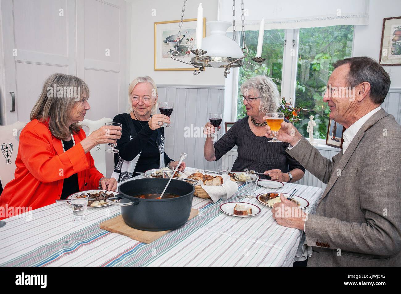 Groupe de personnes ayant dîner à la maison. Des amis heureux assis autour de la table à manger manger de la nourriture et de parler Banque D'Images