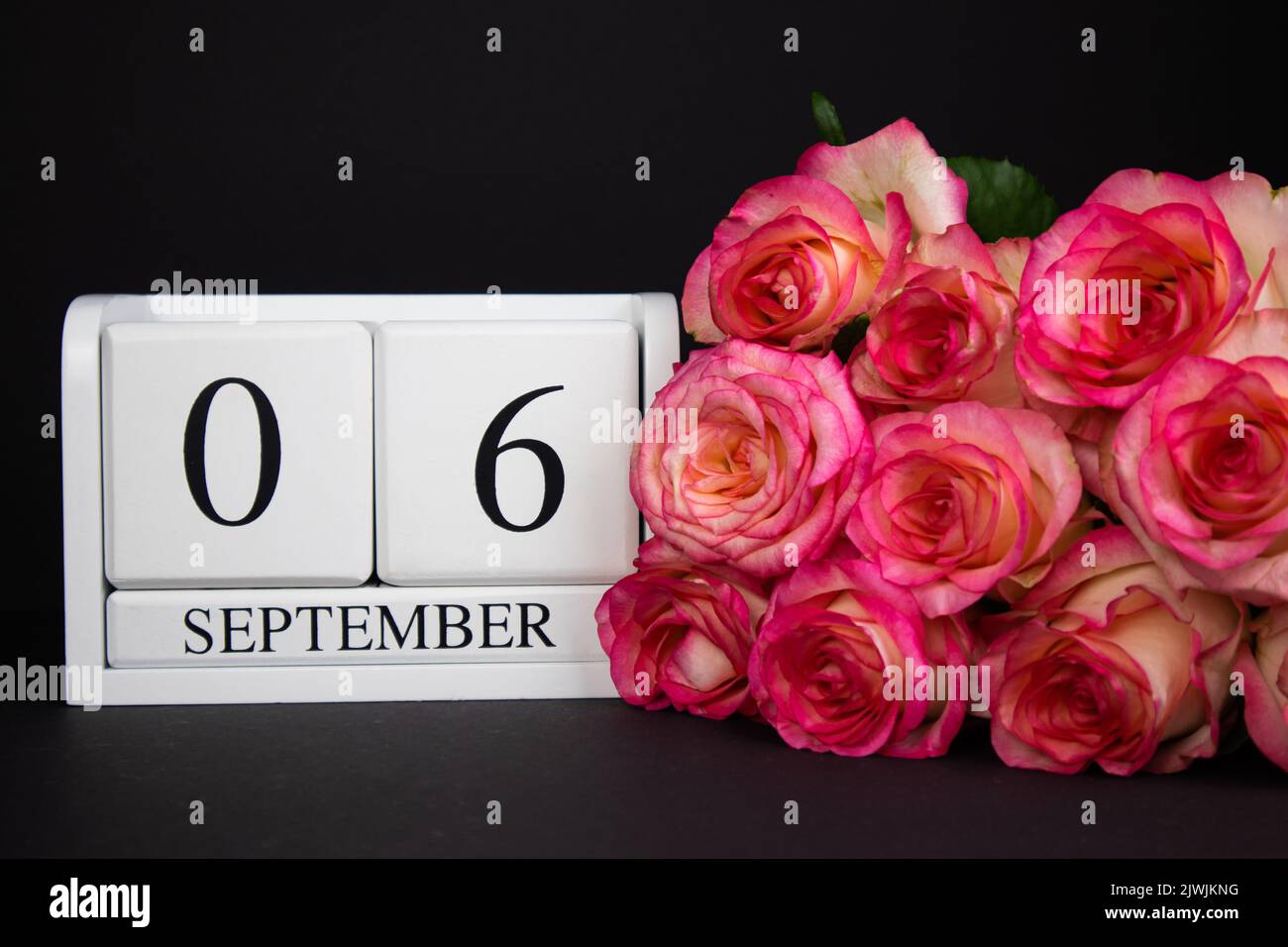6 septembre calendrier en bois, blanc sur fond noir, roses se trouvent à proximité. Banque D'Images