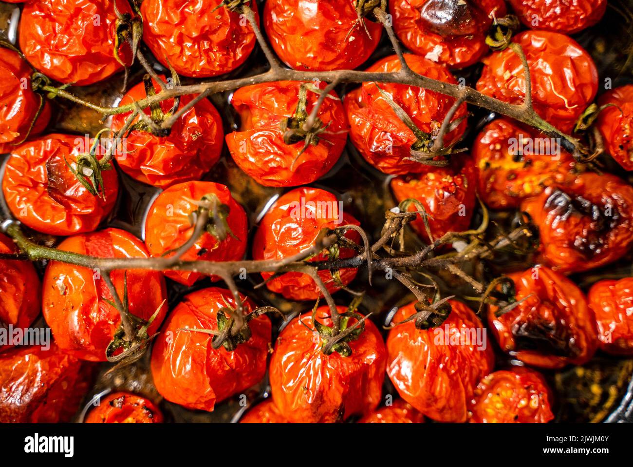 Gros plan de tomates cerises rouges rôties à l'ail, aux herbes et à l'olive Banque D'Images