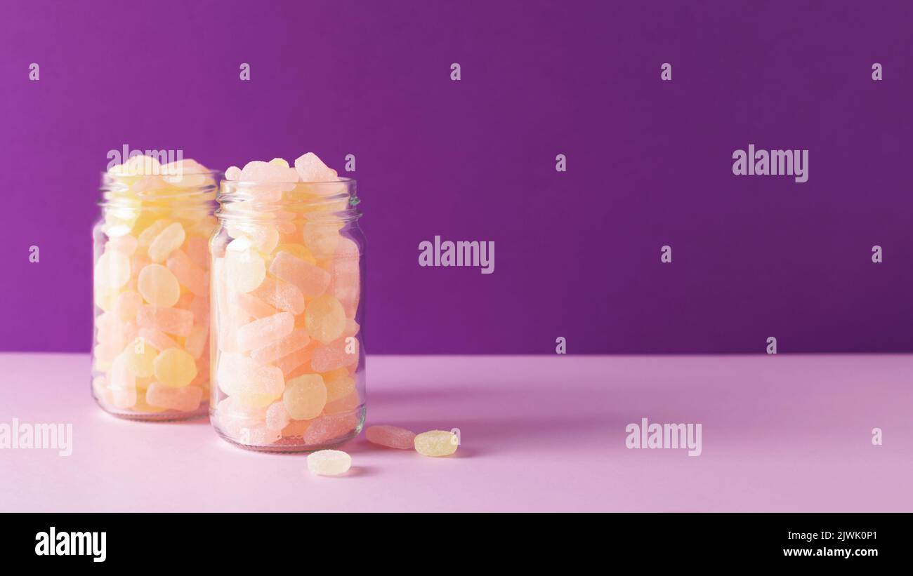 Deux bocaux en verre avec bonbons à la gelée à mâcher sur fond violet. Bannière 16:9. Vue avant. Banque D'Images