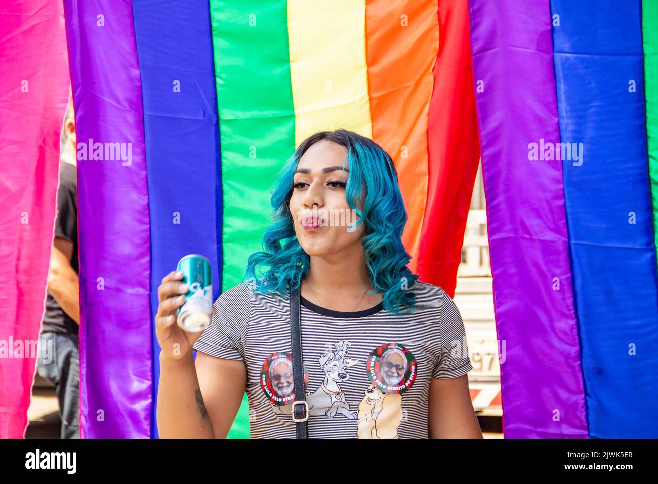 Goias, Brésil – 04 septembre 2022 : une fille souriante, ses cheveux teints en bleu avec des drapeaux arc-en-ciel en arrière-plan. Photo prise pendant la parade. Banque D'Images