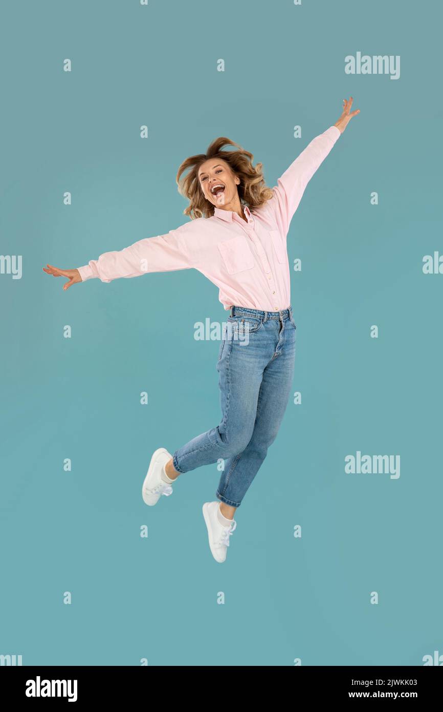Photo verticale de la femme posant en milieu d'air, fond bleu Banque D'Images