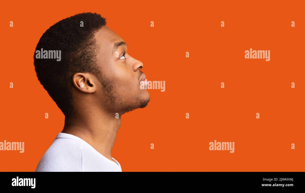 Vue latérale de Serious Black Guy posant sur un fond orange Banque D'Images