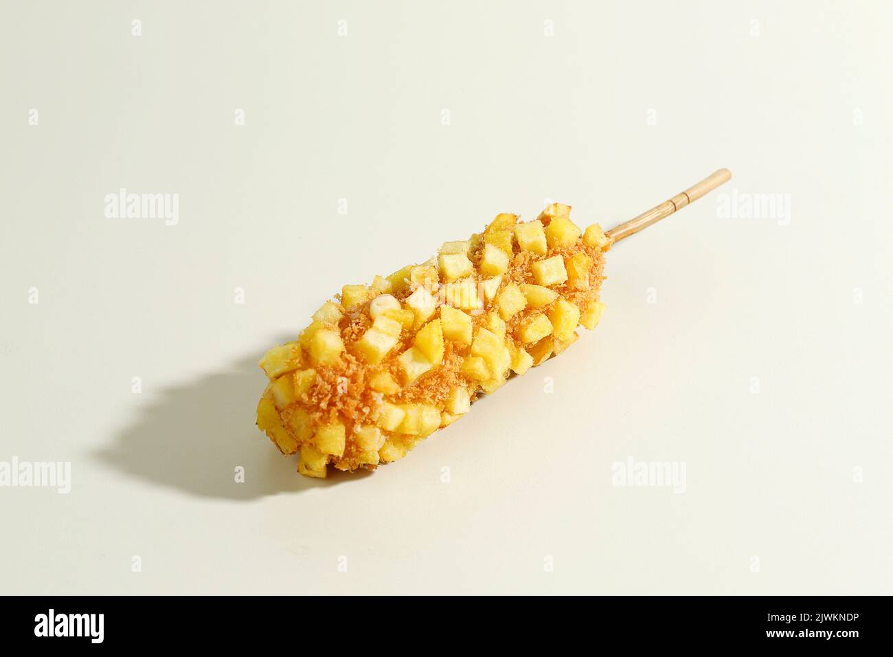 Délicieux croquant Coréen Chunky Potato Corn Dogs avec pâte et pommes de terre frites. Isolé sur fond crème avec espace de copie pour le texte Banque D'Images