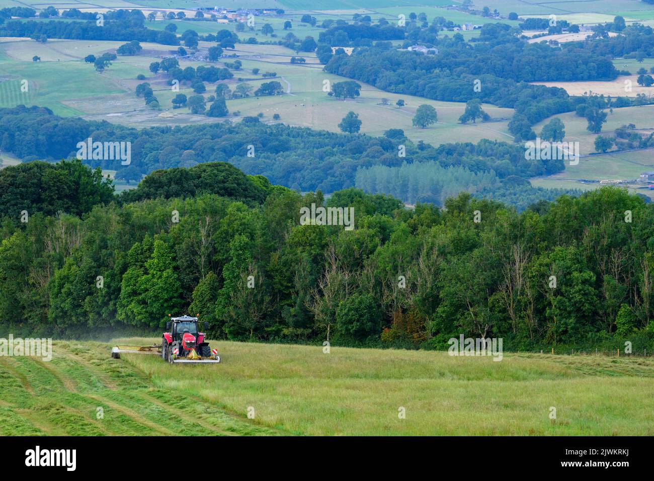 Red Massey Ferguson 7719 S Tractor & Claas Disco 3200c foin marécageuses - pâturage sur les terres agricoles à flanc de colline, campagne pittoresque de Wharfedale, Yorkshire, Angleterre, Royaume-Uni. Banque D'Images