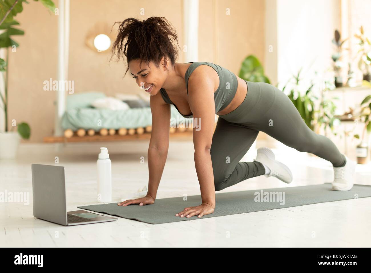 Femme afro-américaine sportive s'entraîner à la maison devant un ordinateur portable et regarder une vidéo de remise en forme Banque D'Images