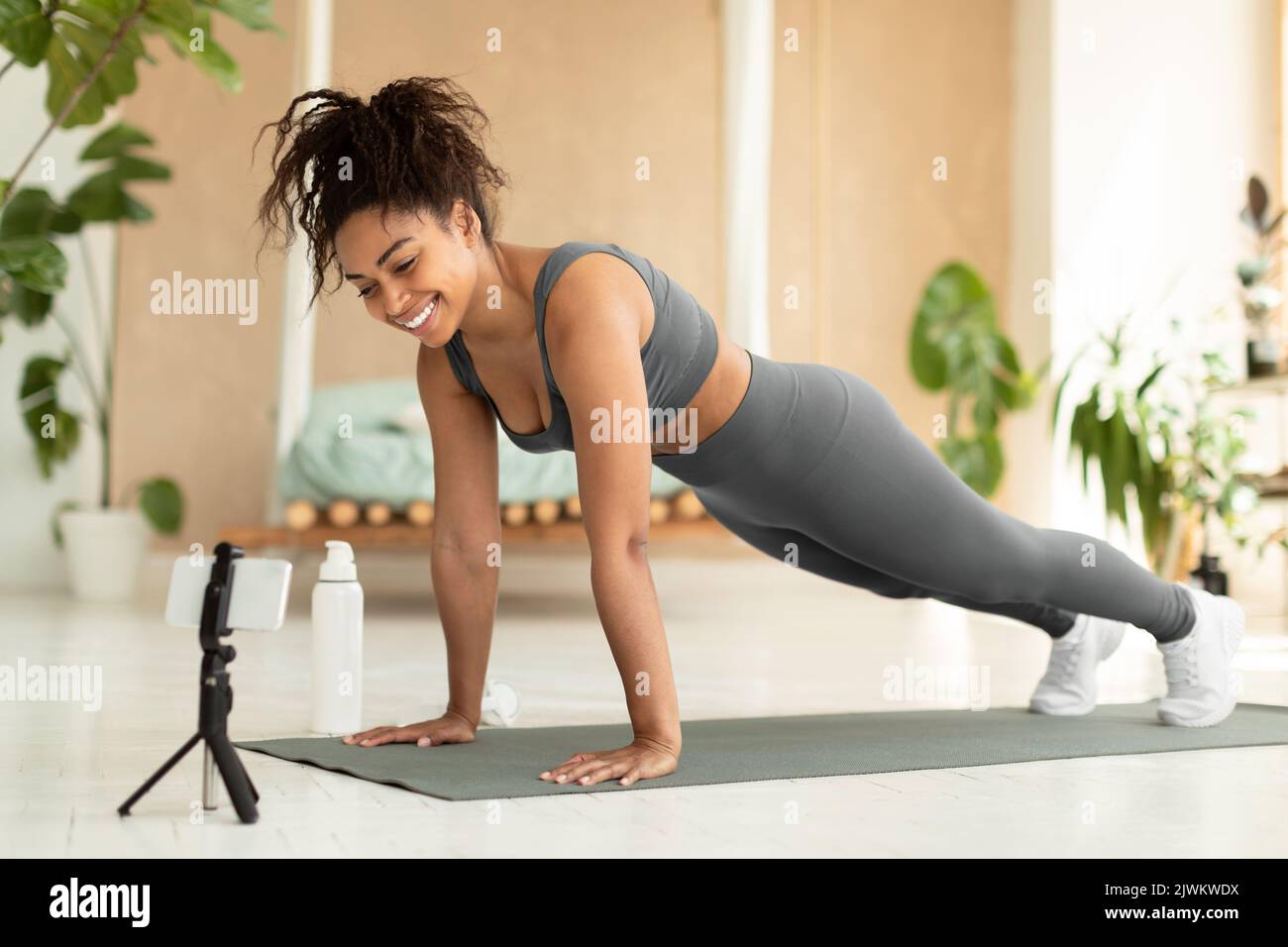 Jeune femme noire planant à la maison, regardant la vidéo de remise en forme ou ayant un appel vidéo avec un entraîneur de remise en forme, espace de copie Banque D'Images