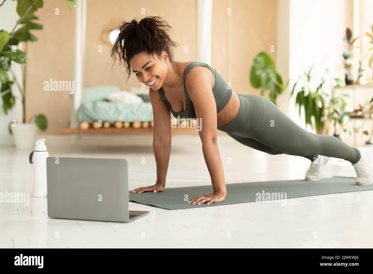 Femme afro-américaine sportive et sportive s'exerçant à la maison, femme noire sportive appréciant un cours de yoga en ligne, à l'aide d'un ordinateur portable Banque D'Images