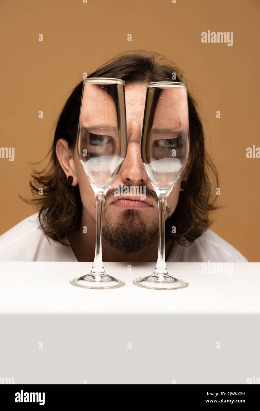 Le visage de l'homme heureux à travers des verres à vin. Distorsion d'objet, illusion optique. Art contemporain minimaliste Banque D'Images