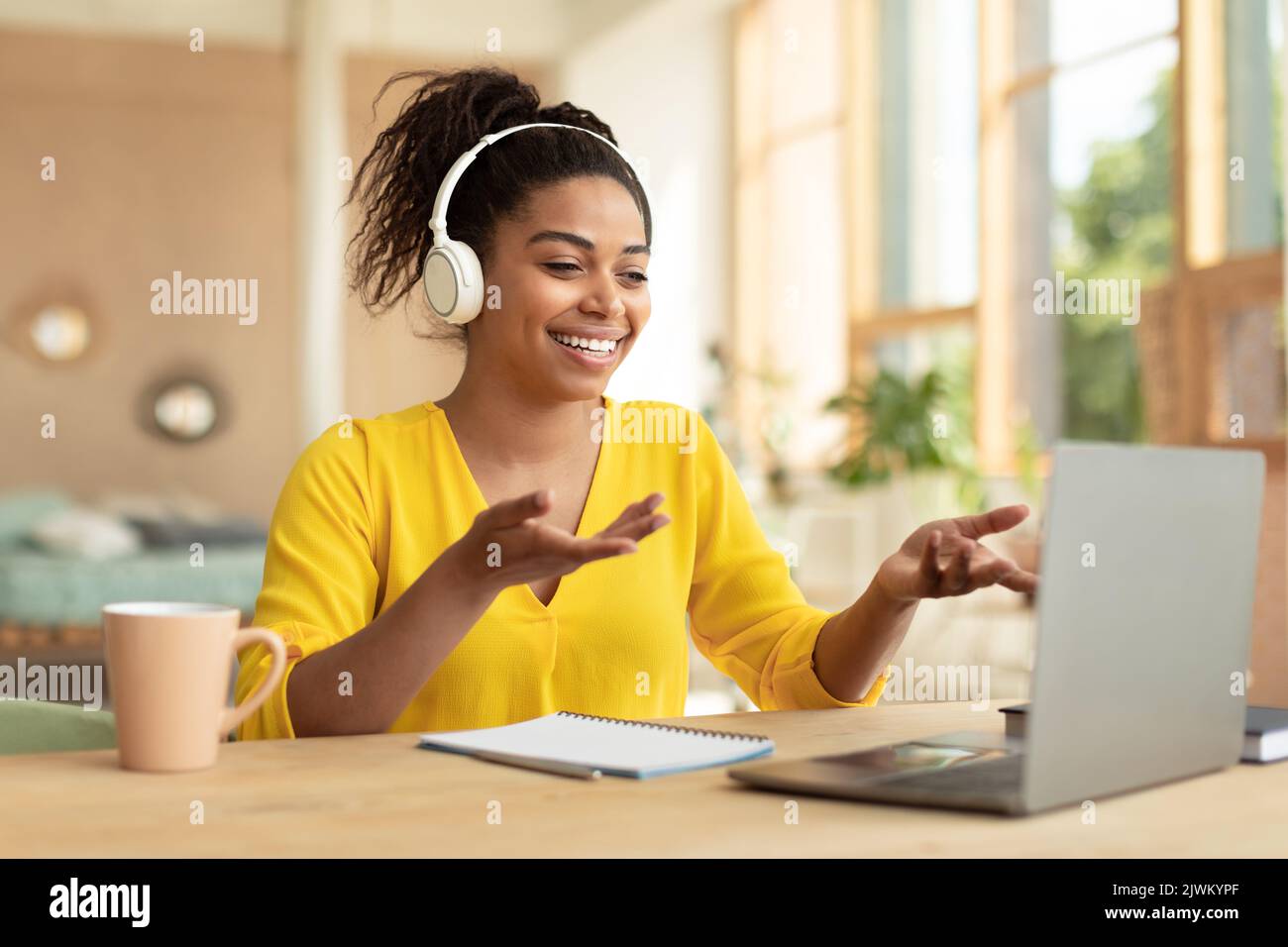 Bonne dame noire dans le casque sans fil appels vidéo via ordinateur portable, communiquant avec un ami ou un étudiant distant Banque D'Images