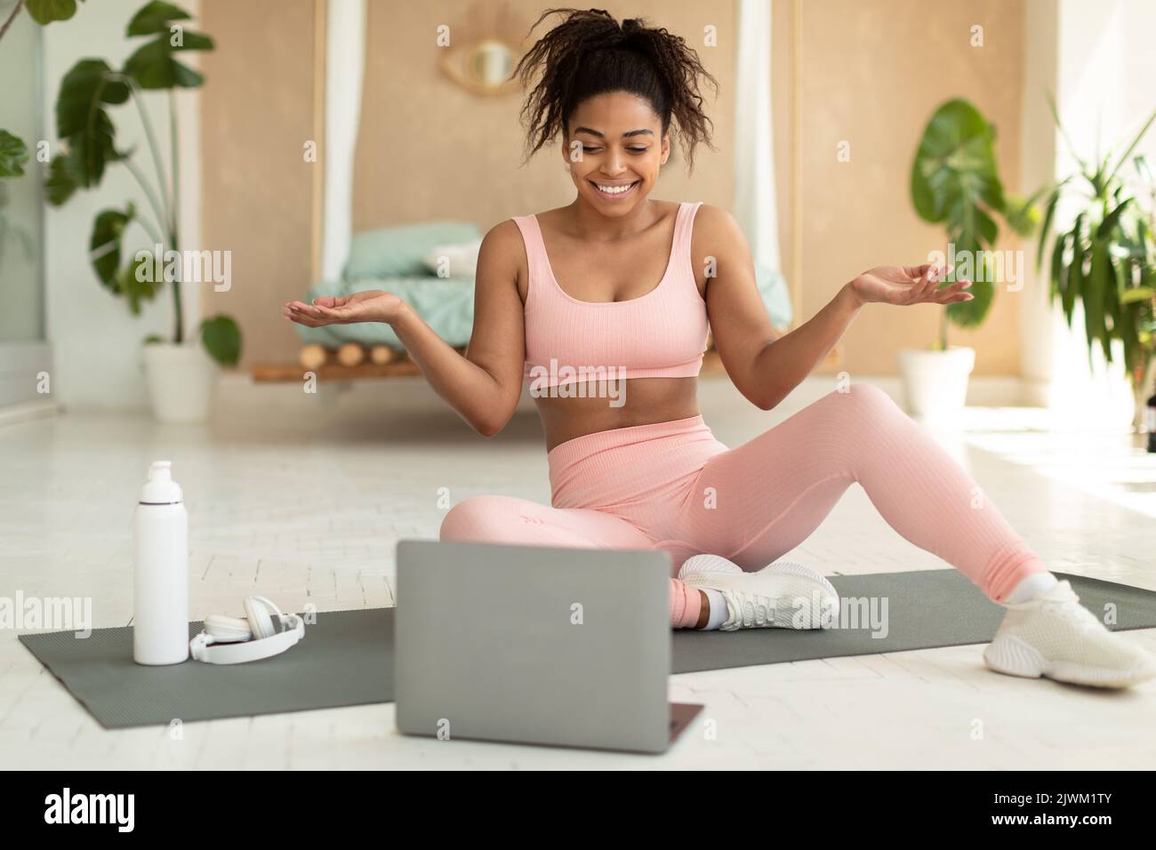 Concept de formation à distance. Bonne femme noire entraîneur ayant cours de fitness en ligne avec ordinateur portable, parlant à l'ordinateur webcam Banque D'Images