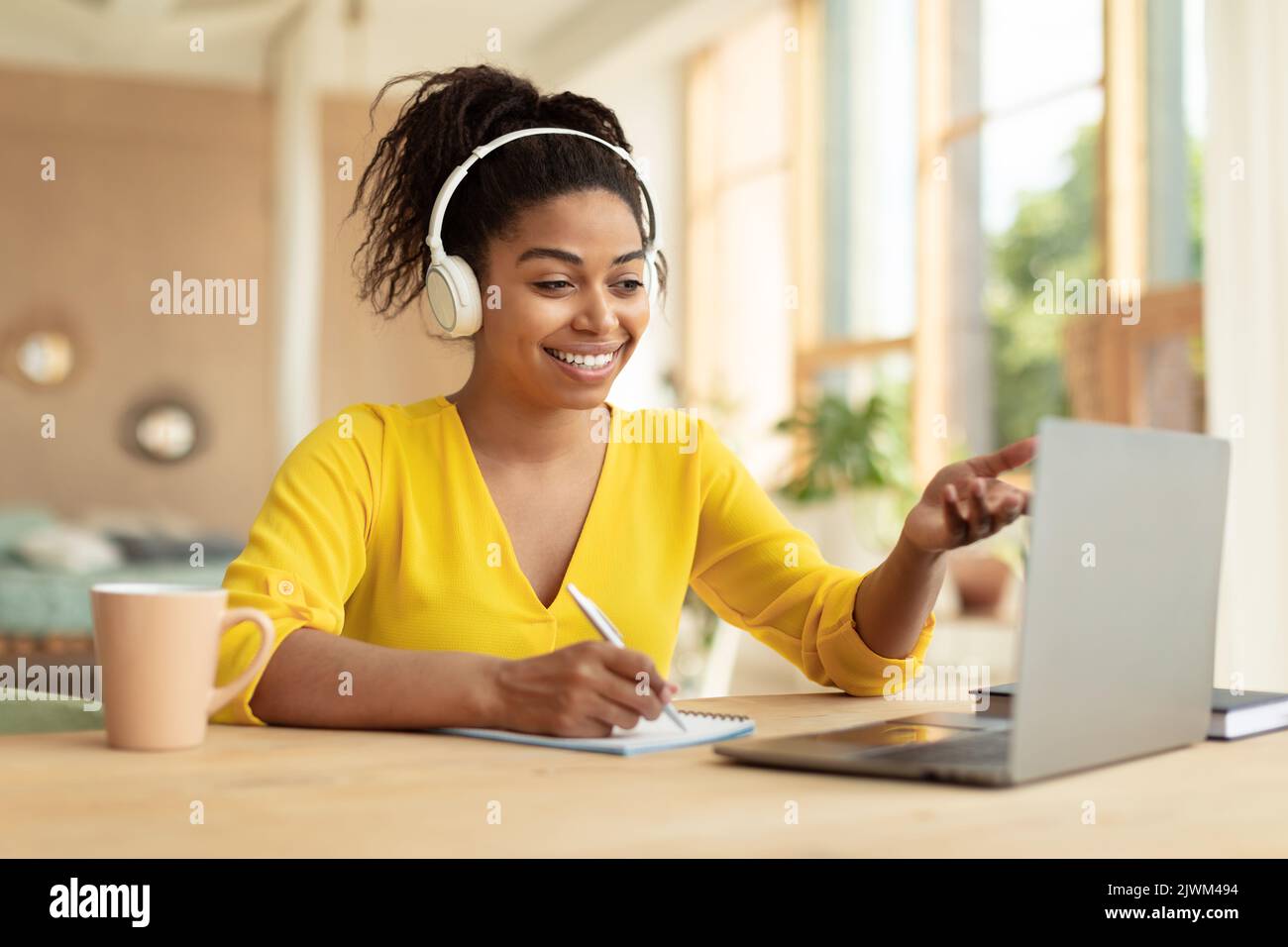Concept de formation en ligne. Bonne étudiante noire dans un casque avec appel vidéo via un ordinateur portable, parler avec un tuteur Banque D'Images