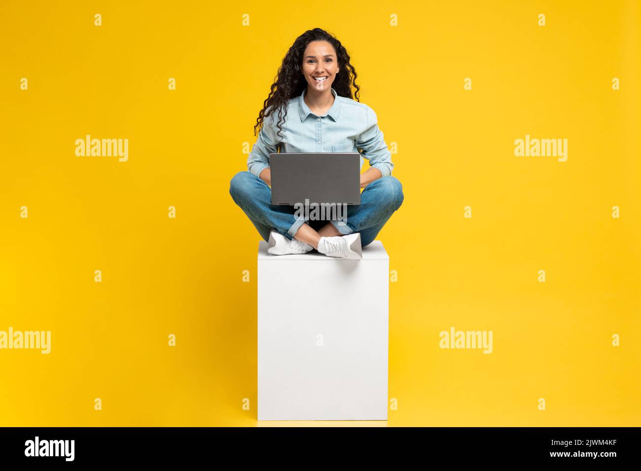 Femme gaie du Moyen-Orient utilisant un ordinateur portable sur fond jaune Banque D'Images