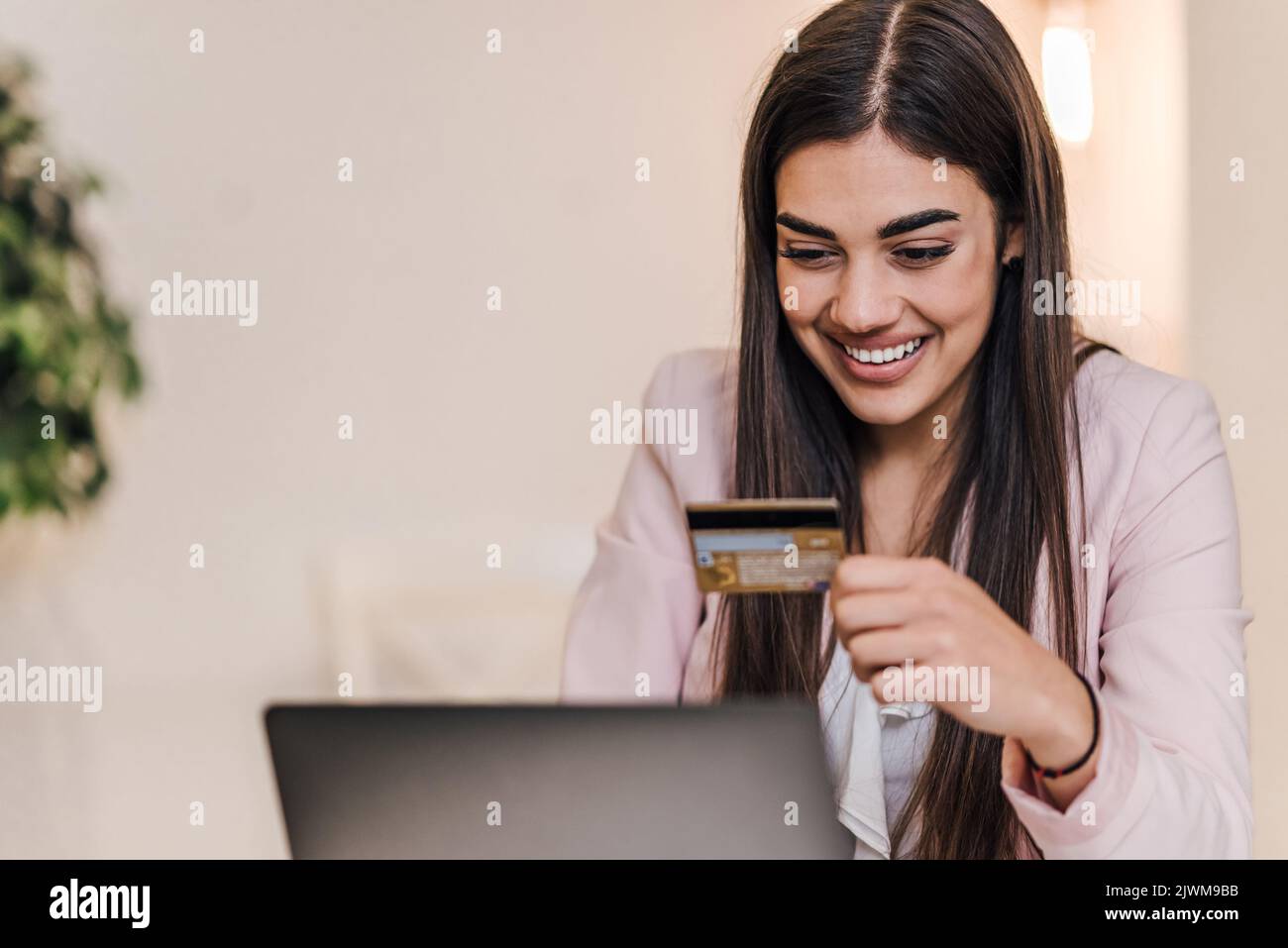 Une jeune femme d'affaires ravie, en vérifiant son numéro de carte de crédit sur son ordinateur portable, au bureau. Banque D'Images