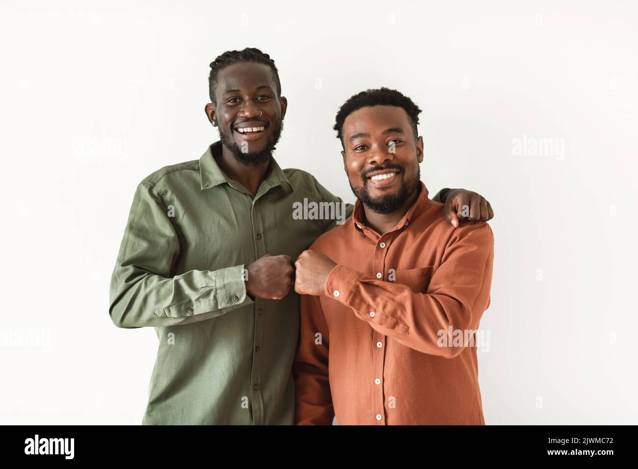 Deux gars afro-américains heureux qui se sont fait passer les poings sur fond blanc Banque D'Images