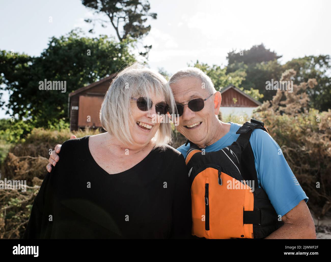 un couple à la retraite riant à la plage prêt à pratiquer des sports nautiques Banque D'Images
