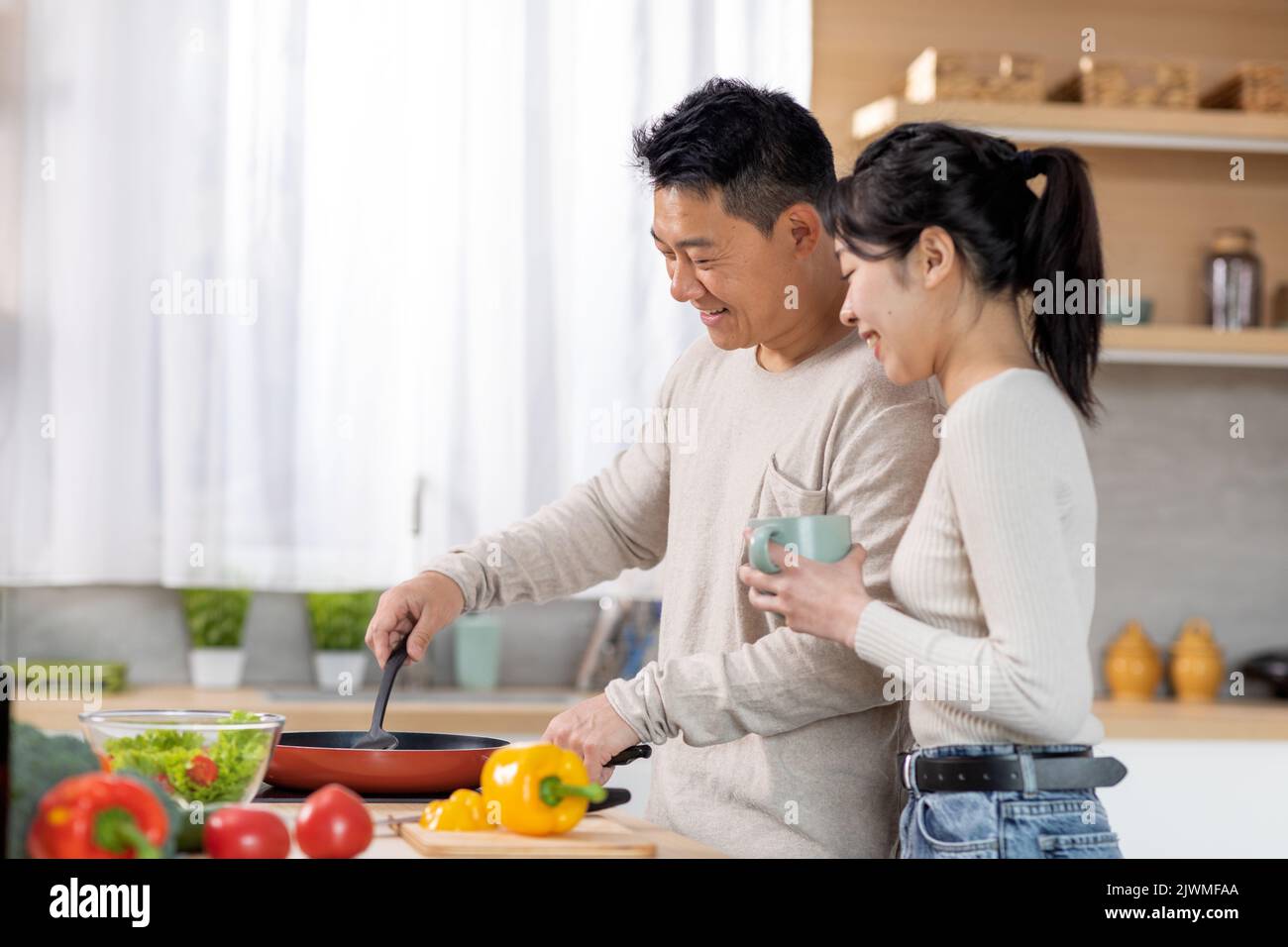 Un mari chinois affectueux qui cuisine un dîner pour sa belle femme Banque D'Images