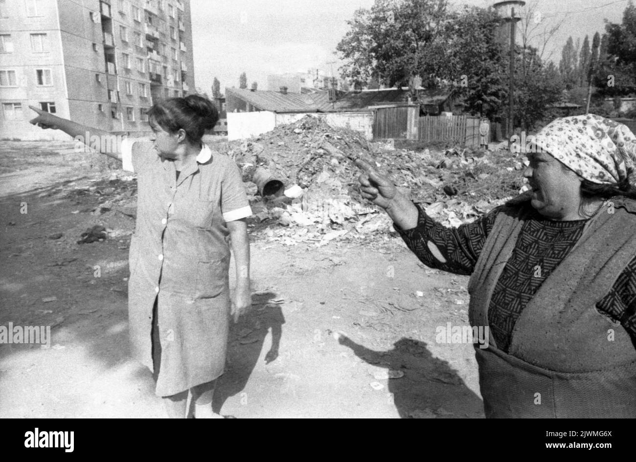 Bucarest, Roumanie, cca 1992. Femme concierges par des piles de détritus dans une rue du quartier. Banque D'Images